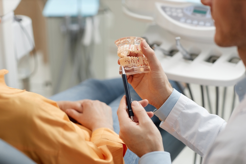 Dental Consultation with Jaw Model - Dental Crowns in Bakersfield Dentist explaining oral health using a dental jaw model during consultation. Ideal for educational content on dental care, implants, and treatment planning. - Dental Crowns in Bakersfield