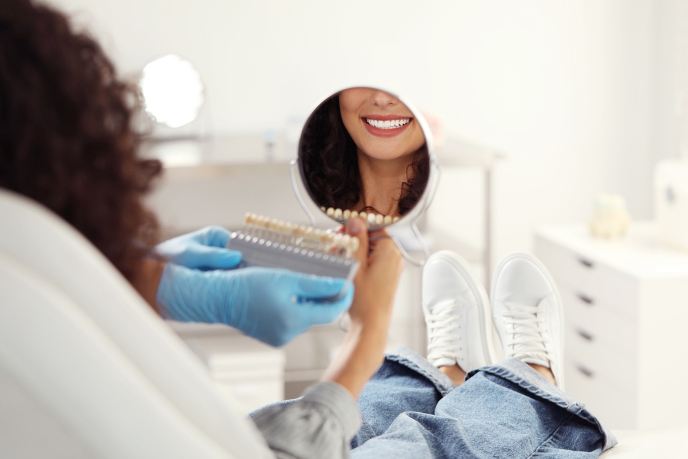 Patient Smile in Mirror – Dental Shade Matching Consultation - Veneers in Bakersfield Woman admiring her smile in a mirror during a dental shade matching session. Great for content on cosmetic dentistry, veneers, and smile makeovers. - Veneers in Bakersfield