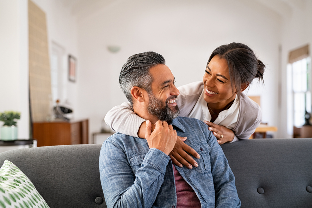 Happy Couple Smiling Together at Home - Bakersfield Orthodontist Loving couple sharing a joyful moment on the couch at home. Perfect image for themes of love, relationships, connection, and family lifestyle. - Bakersfield Orthodontist