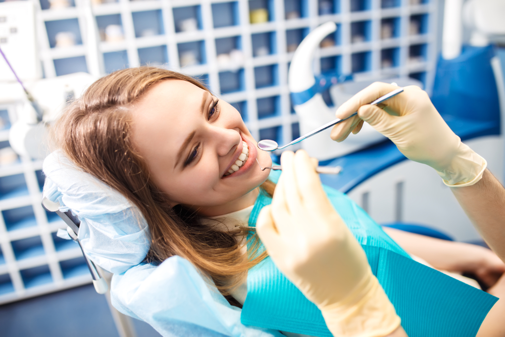 Happy Woman at Dentist – Professional Dental Examination - Dental Implants in Bakersfield Young woman smiling during a dental checkup. Great for general dentistry, oral hygiene awareness, and patient-friendly clinic visuals. - Dental Implants in Bakersfield