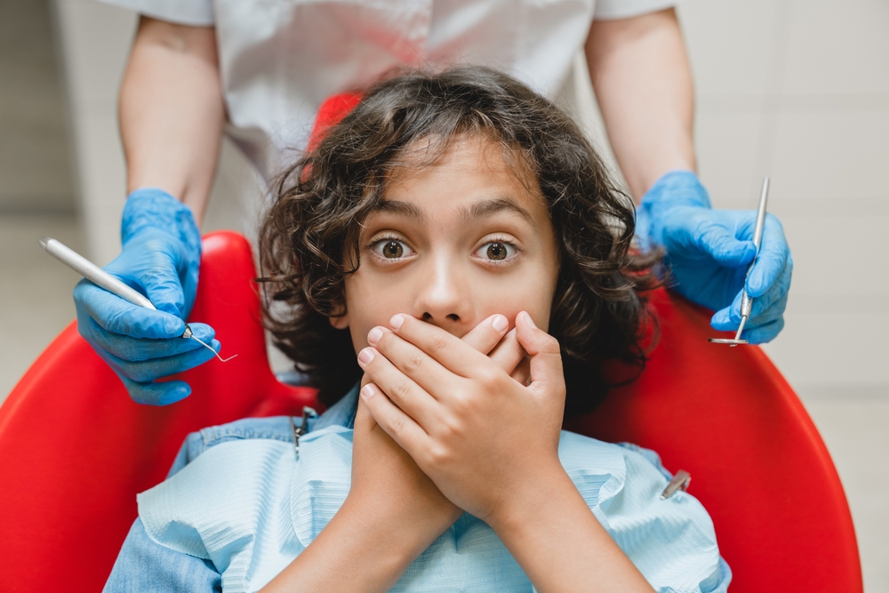 Nervous Child at Dentist - Pediatric Dentist Bakersfield Young child covering mouth in fear during a dental visit, highlighting dental anxiety in kids. Ideal for pediatric dentistry and oral health awareness topics. - Pediatric Dentist Bakersfield