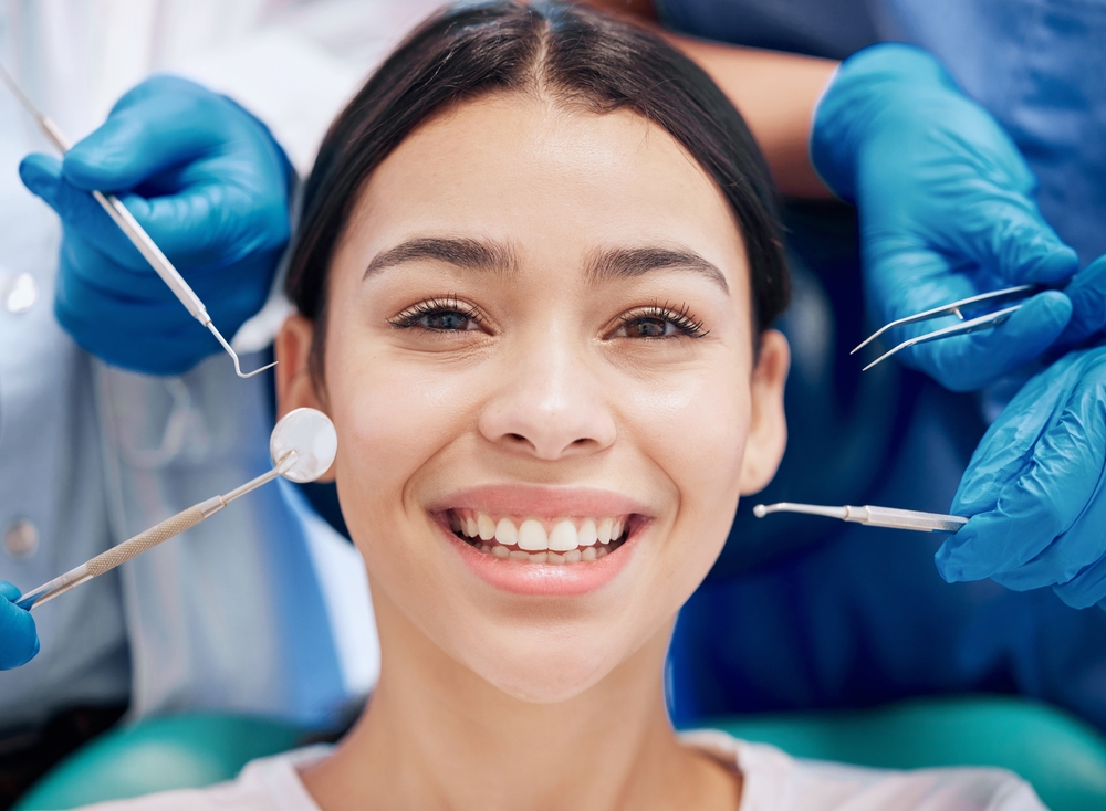 Smiling Woman at Dentist – Comprehensive Dental Checkup Young woman smiling confidently during a dental exam surrounded by dental tools. Ideal for general dentistry, oral care, and preventive treatment visuals.